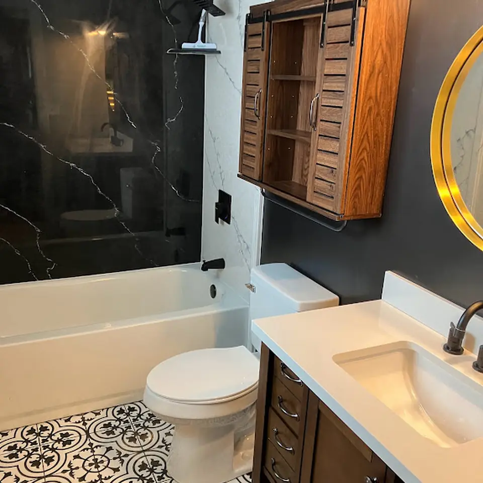 Remodeled bathroom with black marble-look tile, patterned floor, and dark vanity