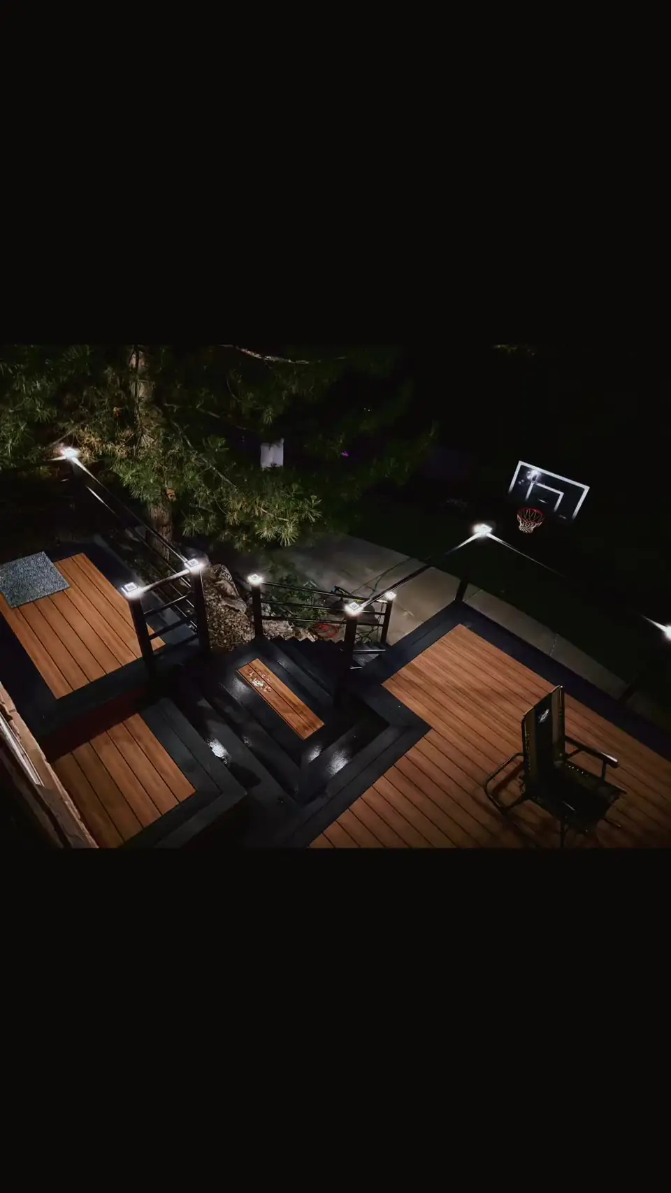 Multi-level composite deck with modern railings and integrated post lighting at night