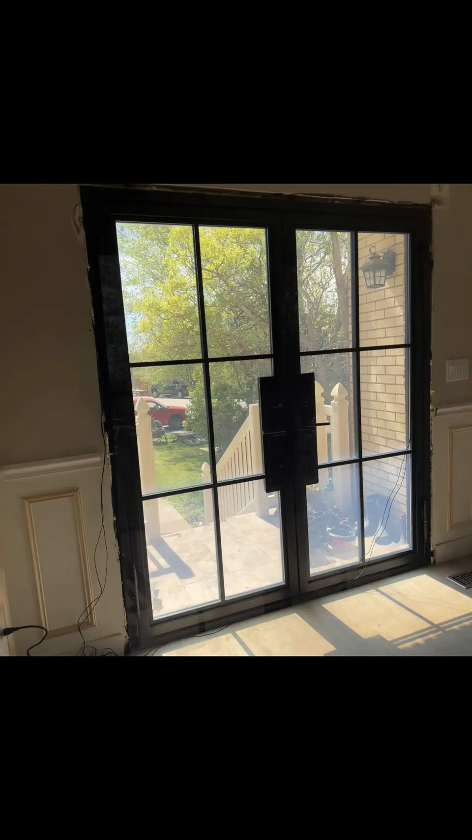 Double black-frame glass doors looking out to a patio during a remodel