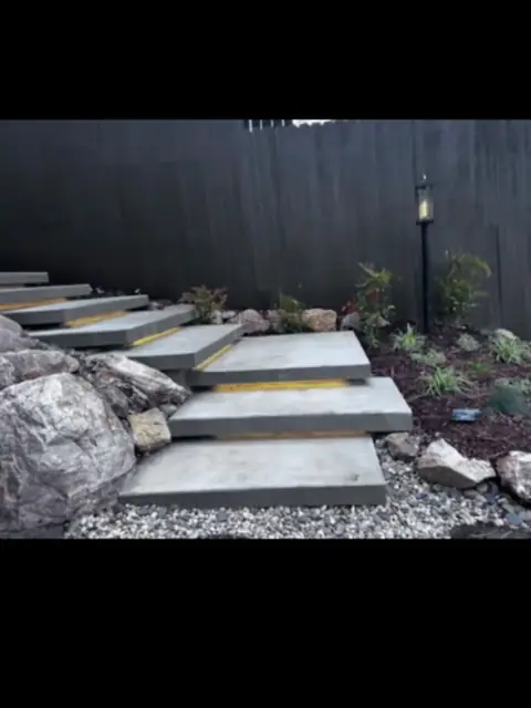 Modern floating concrete stairs with warm LED under-step lighting at night