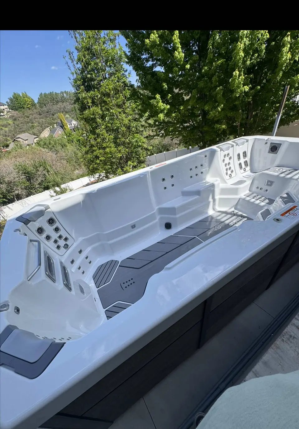 Swim spa sitting on a finished concrete pad in a backyard